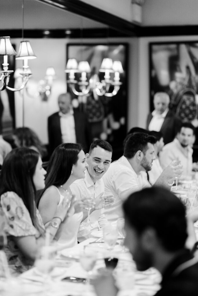 Bride and groom smiling during toasts at rehearsal dinner