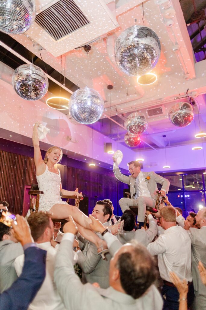 bride and groom lifted in chair at reception 