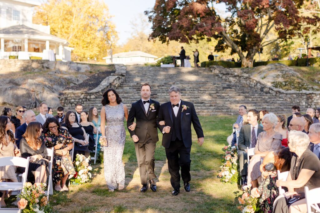 groom walking down the aisle by parents