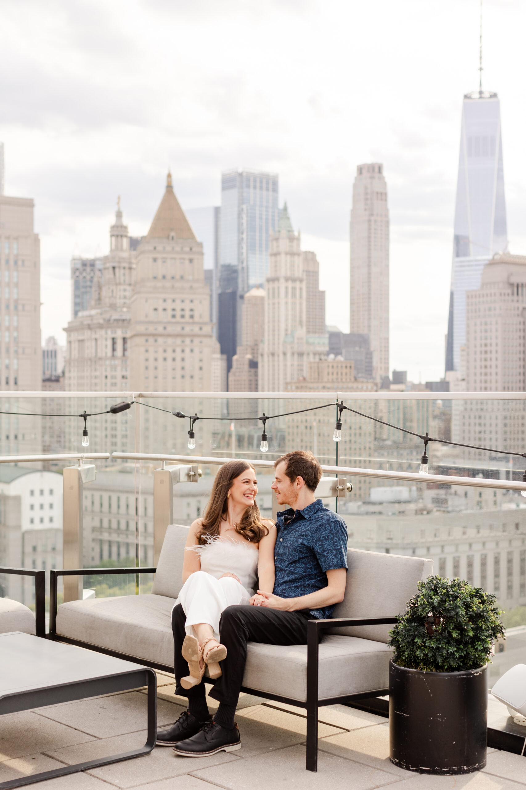 NYC rooftop welcome party, couple sitting down posing with the NYC skyline in the backdrop