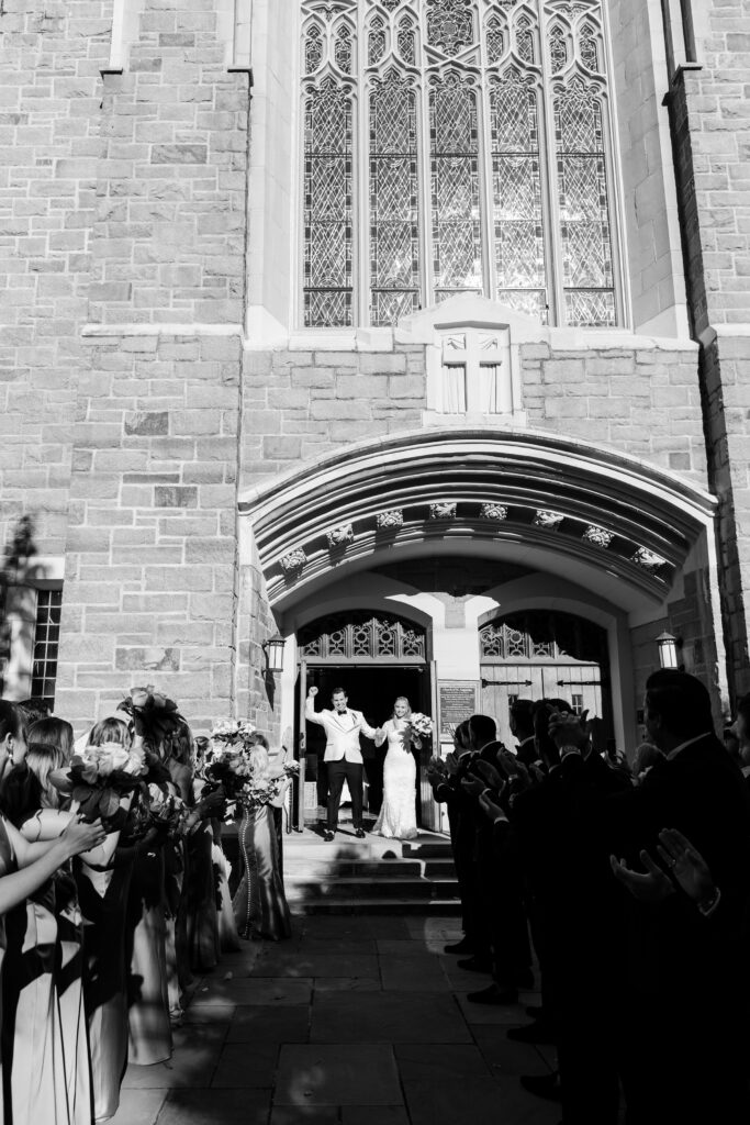 bride and groom grand exit at church lined with guest cheering