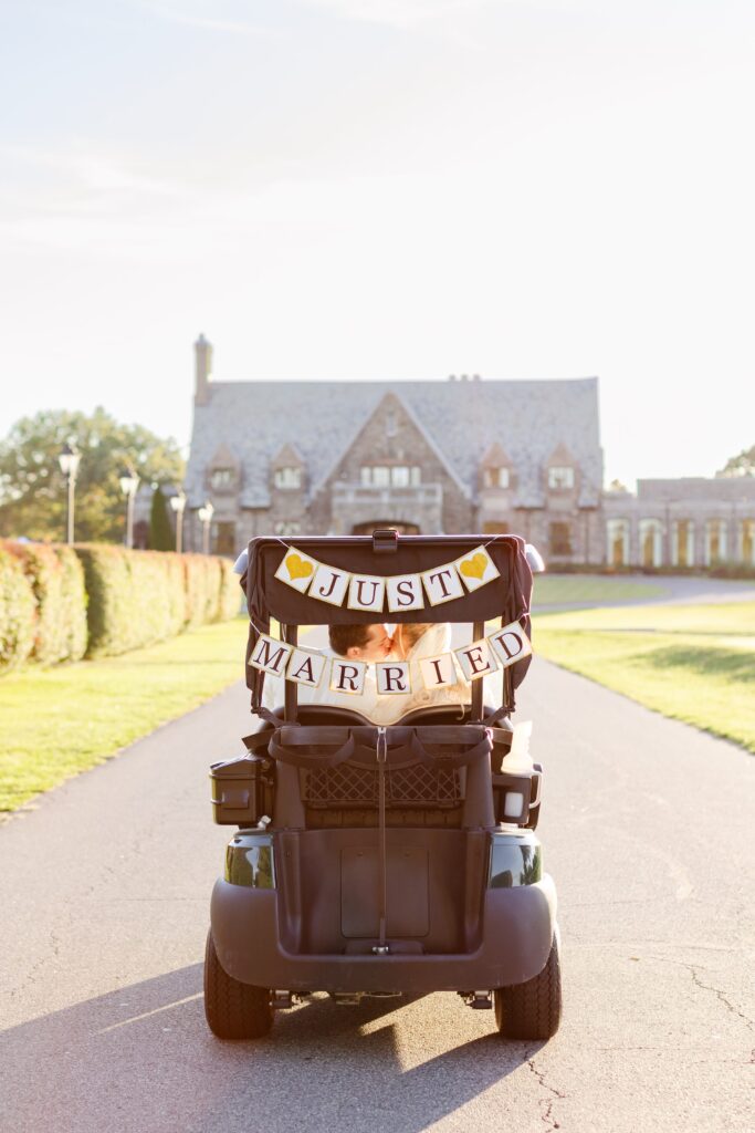 bride and groom kissing in golf cart in front of Winged Foot Golf Club, bride and groom portraits at Winged Foot Golf Club 