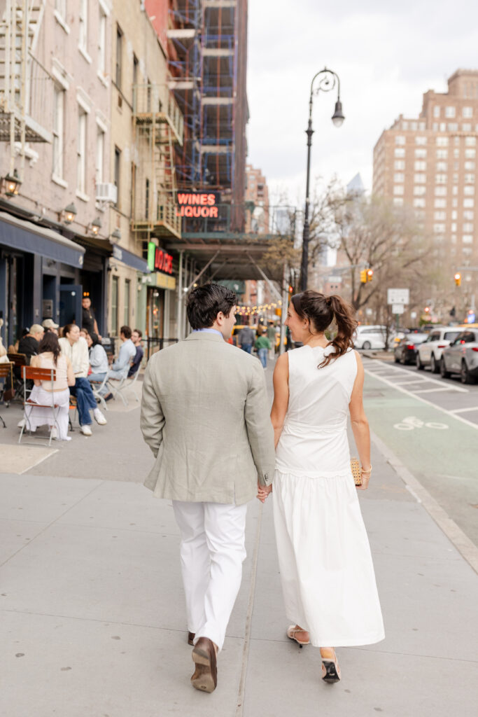 couple holding hands walking down West Village in front of Hudson Hound for their engagement photos