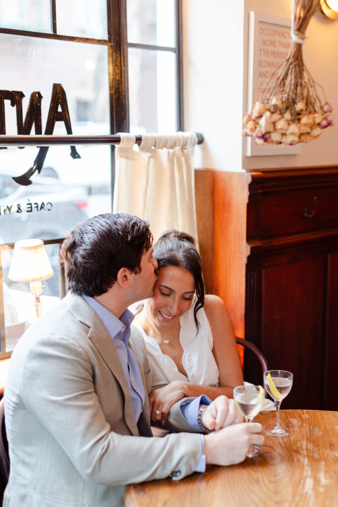 couple cuddling at a table during engagement photos at Anton's