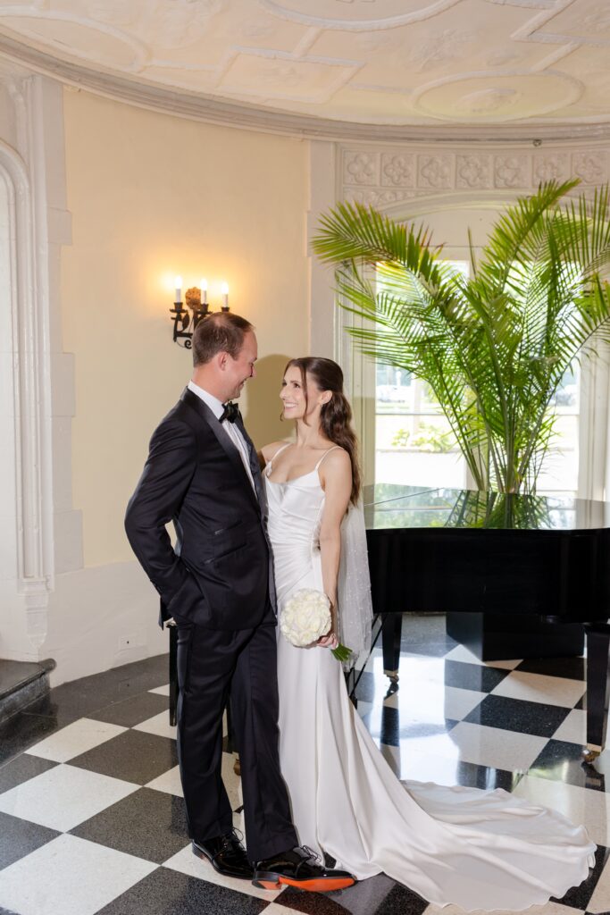 Bride and Groom smiling during portraits by the grand piano at Westchester Country Club