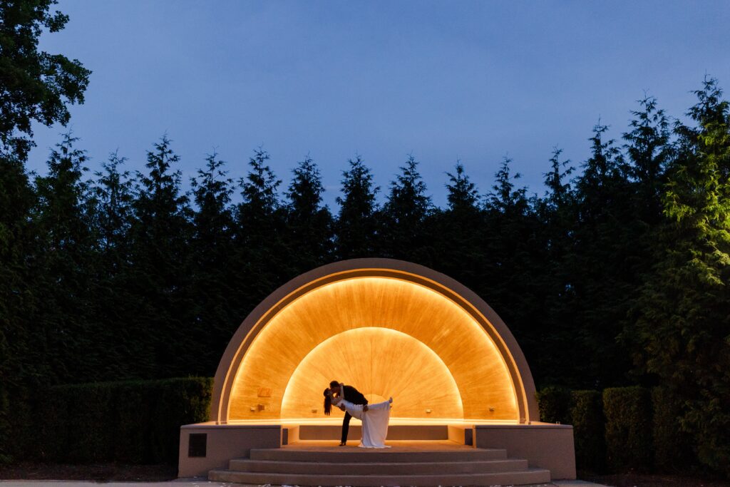 couple kissing during night portraits in front of the illuminated bandshell