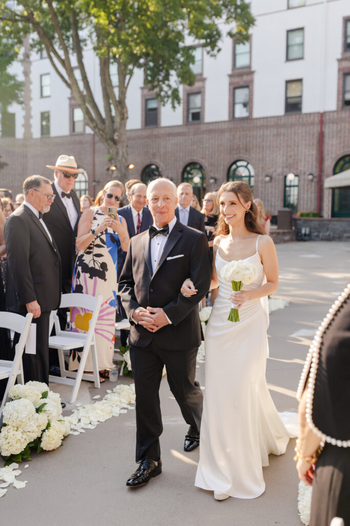 bride and father of the bride walking down the aisle for their outdoor summer wedding at Westchester Country Club in front the bandshell