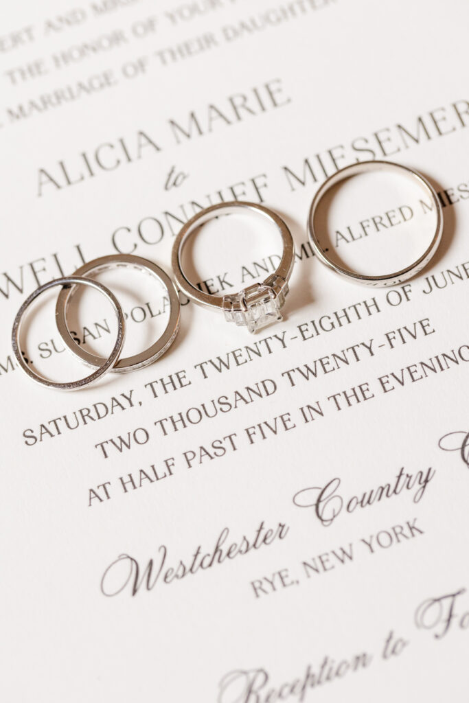 close up of wedding rings over the wedding invitation