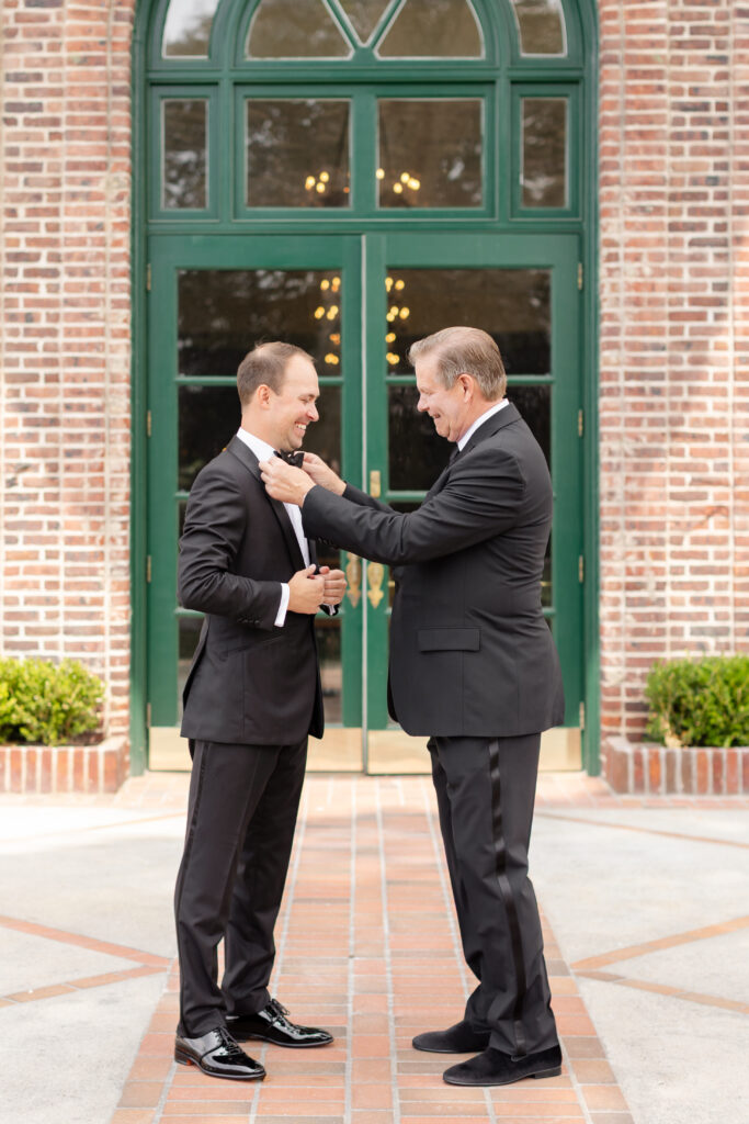 groom getting ready and father helping adjust bow tie