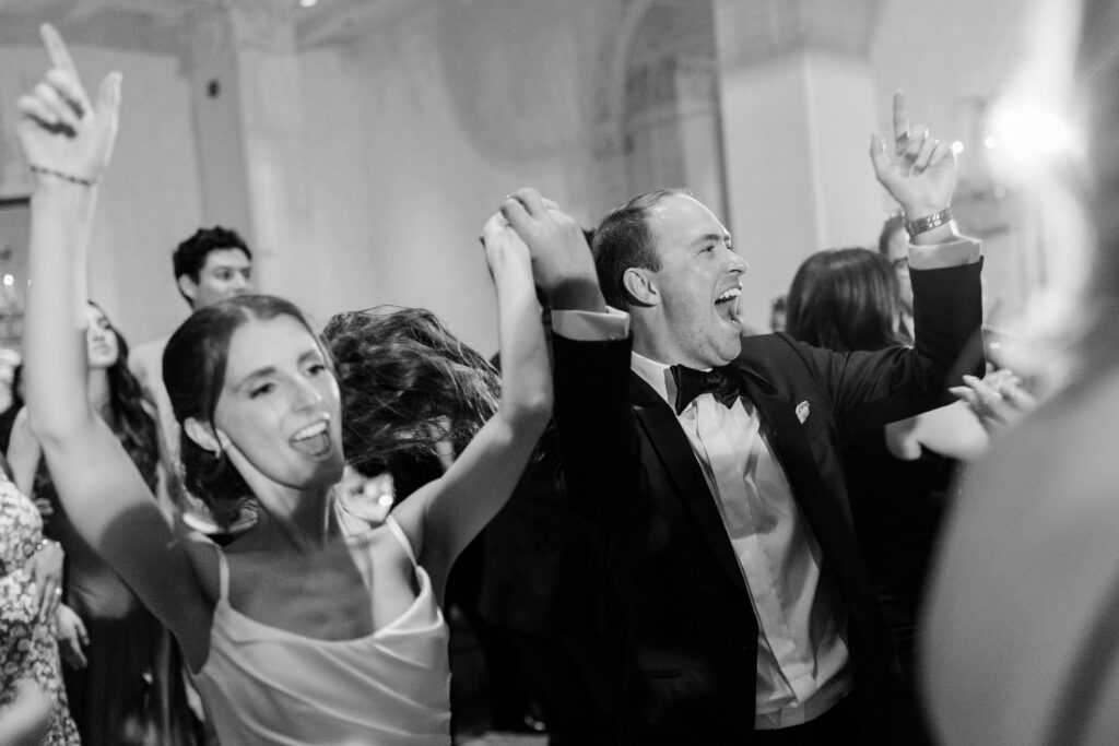 bride and groom laughing, holding hands, and dancing during the reception