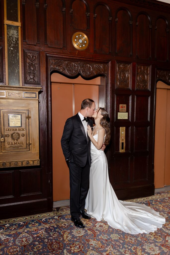 bride and groom kissing in front of the vintage elevator at Weschester Country Club