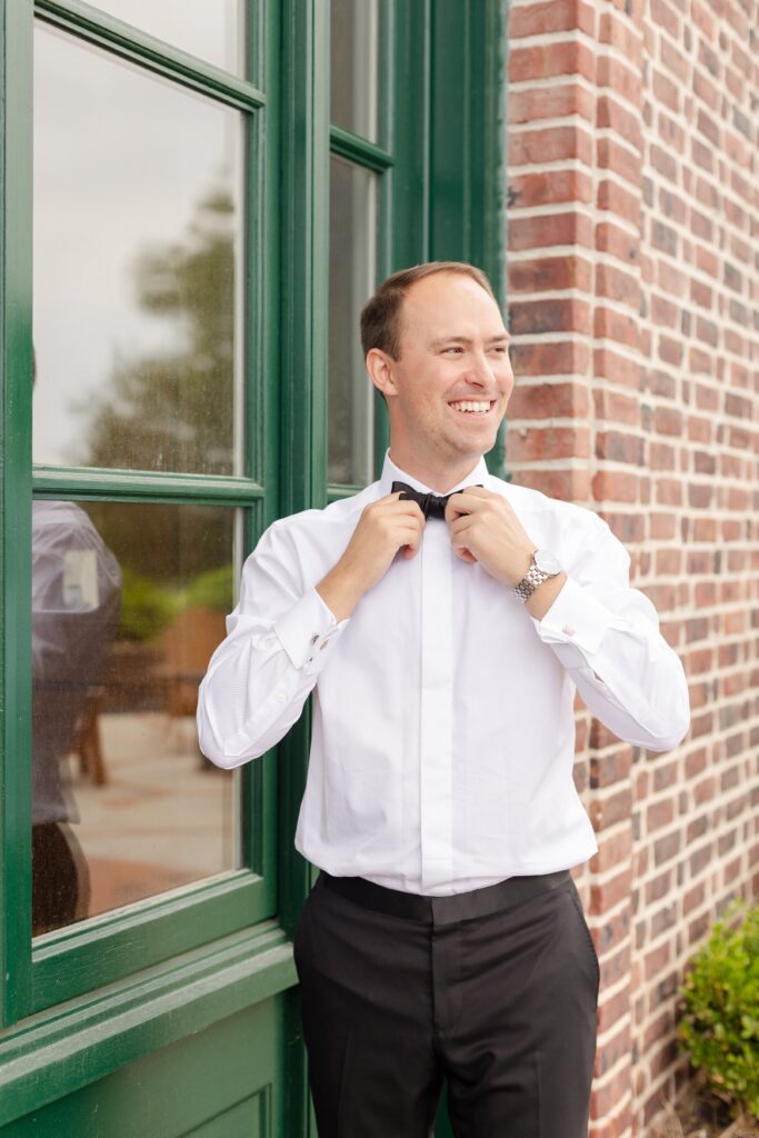 groom getting ready and helping adjust bow tie