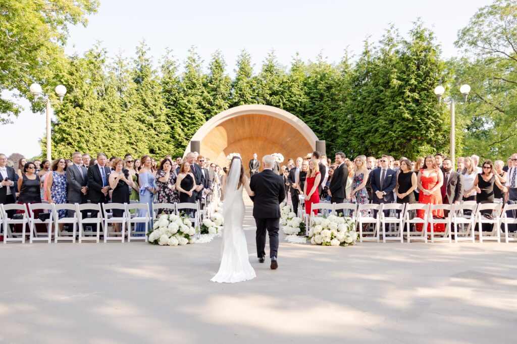 bride and father of the bride walking down the aisle for their outdoor summer wedding at Westchester Country Club in front the bandshell