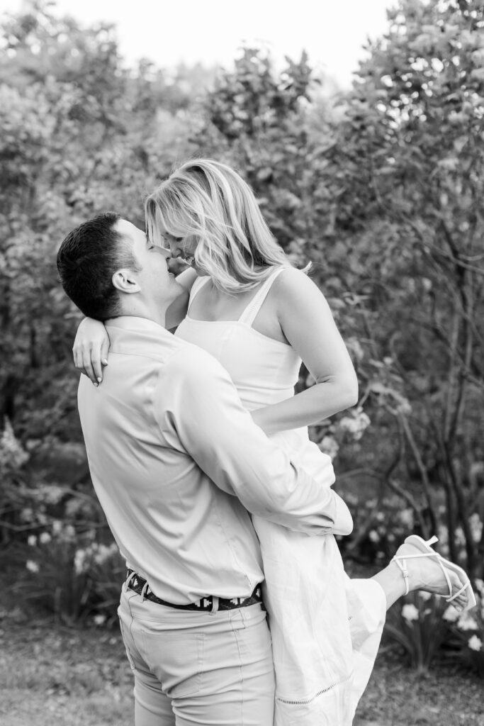 guy holding fiance in the air going in for a kiss during NYC engagement session in Central Park