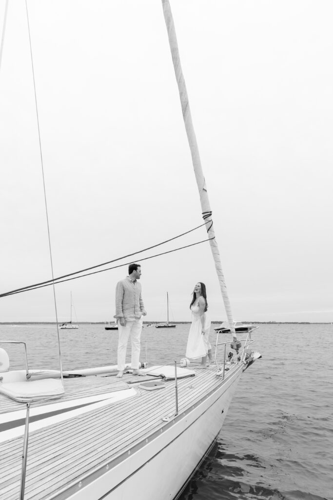 couple laughing and walking on the sailboat during their engagement session at Larchmont Yacht Club