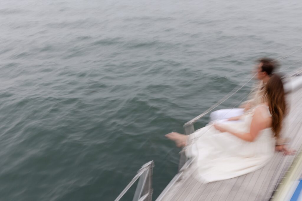 couple hanging feet off side of sailboat during engagement session