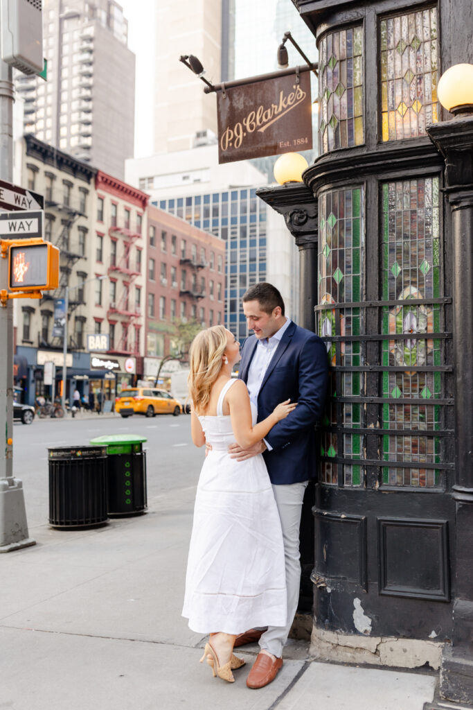 couple embracing on the streets of New York in front of PJ Clarke's Restaurant, NYC Engagement Locations