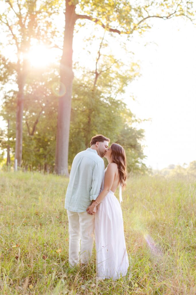 couple kissing in a field during their engagement session at Rockefeller State Park