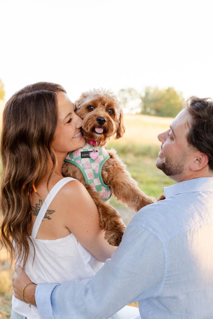 couple smiling and holding their dog