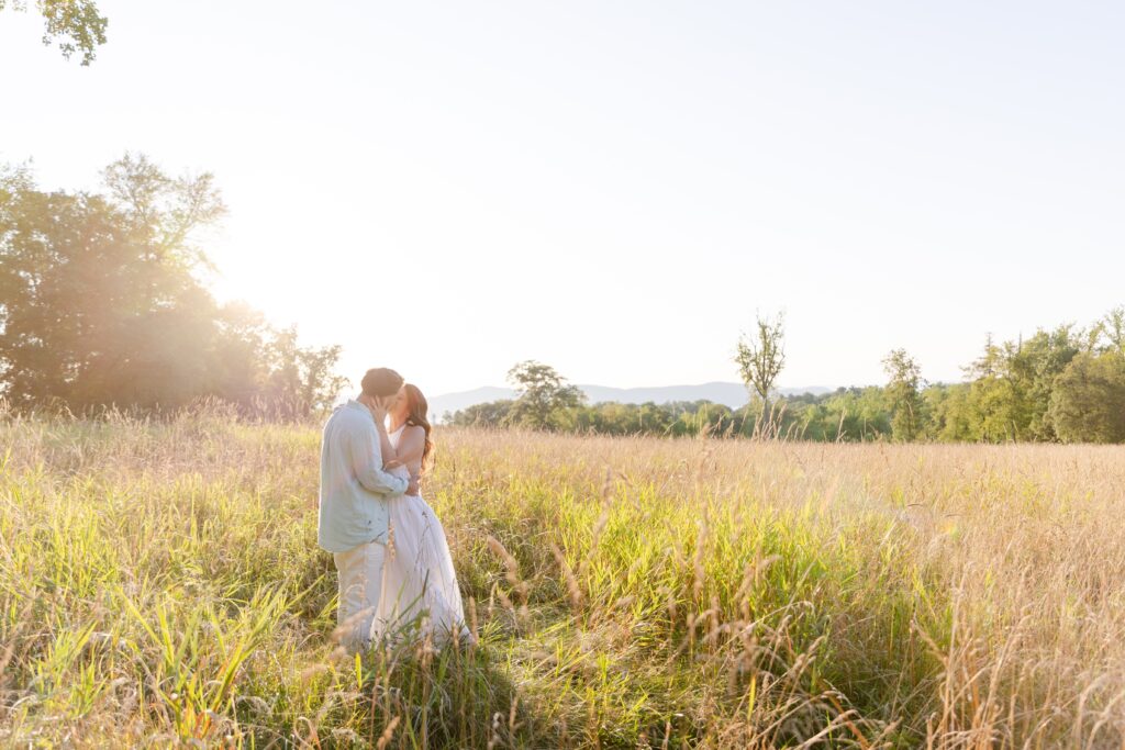 couple kissing in a field during their engagement session at Rockefeller State Park