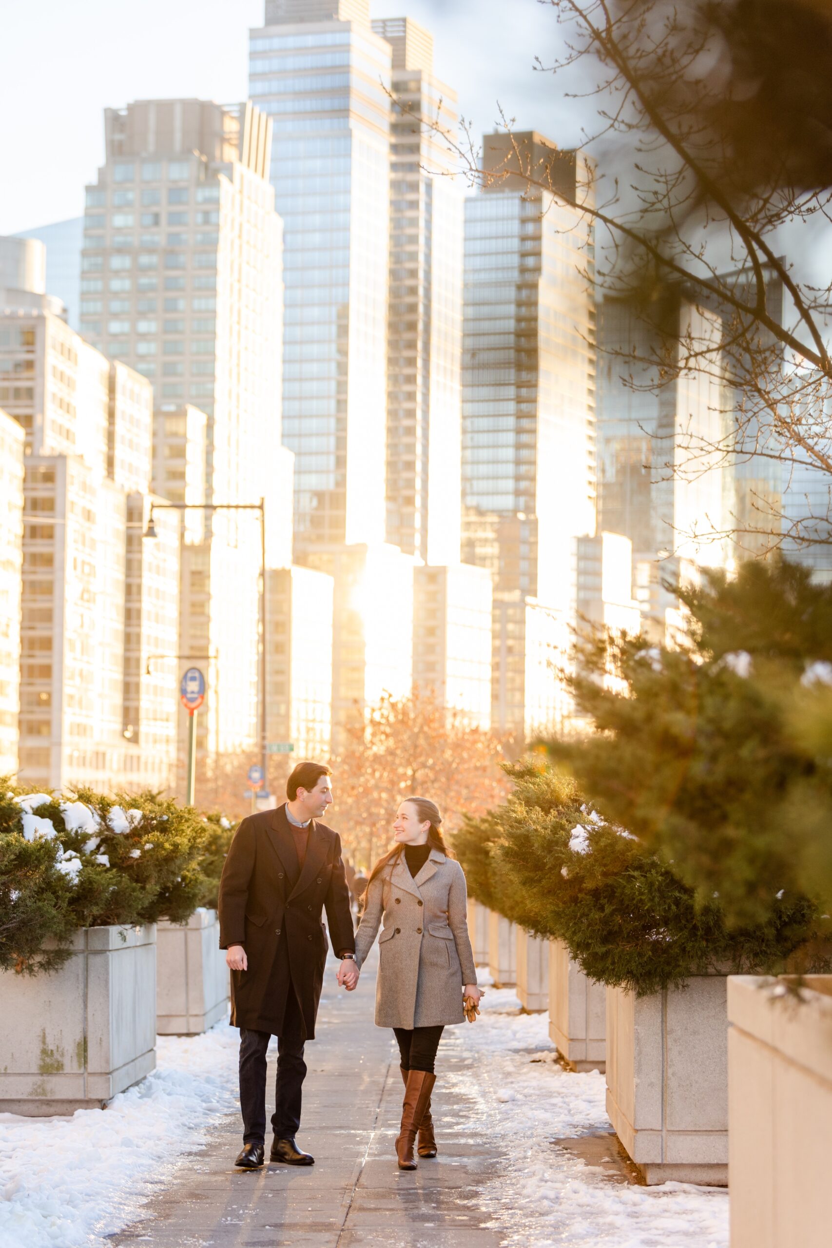 couple holding hands walking in snowy NYC streets at sunset